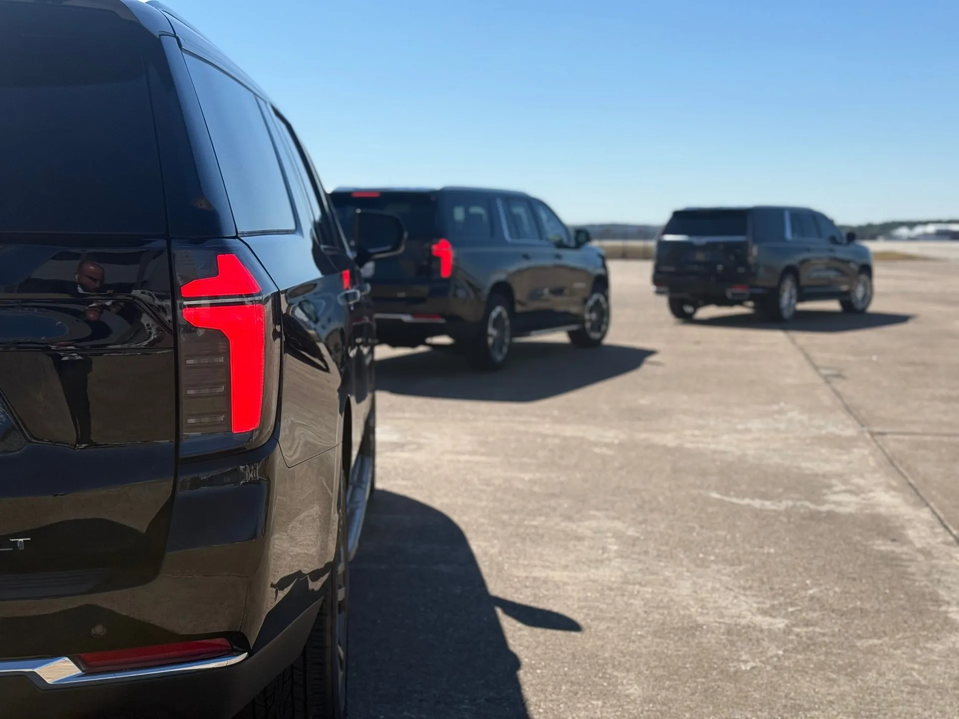 Black SUVs staged for a departure from an airport