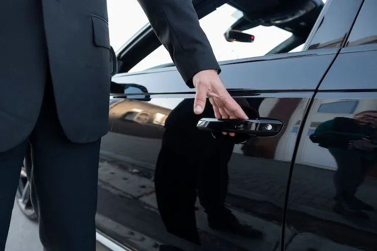 Chauffeur opening the door of a black luxury sedan